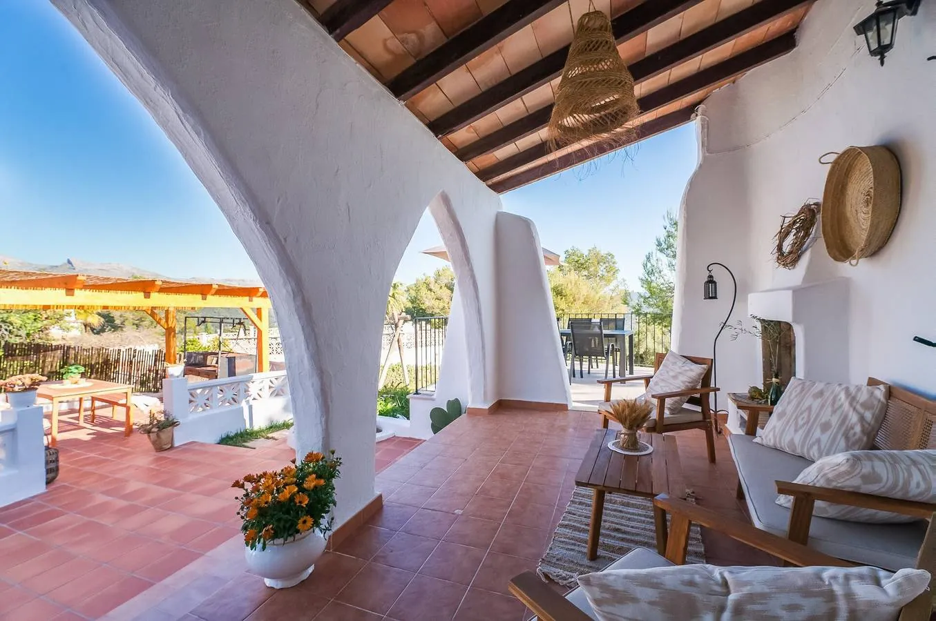 Whitewashed arched porch with a fireplace and armchairs
