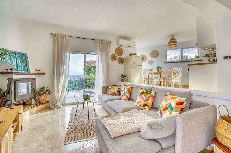 Living room with sofa and wood-burning stove, open to the kitchen and the terrace